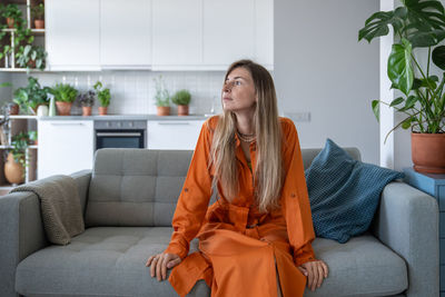 Young woman sitting on sofa at home