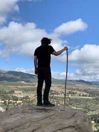 Rear view of man standing on mountain against sky