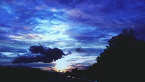 Silhouette of trees against cloudy sky