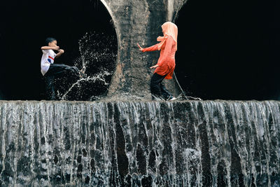 Mother with son enjoying waterfall on rock formation