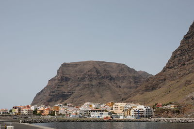 Buildings by mountain against clear sky