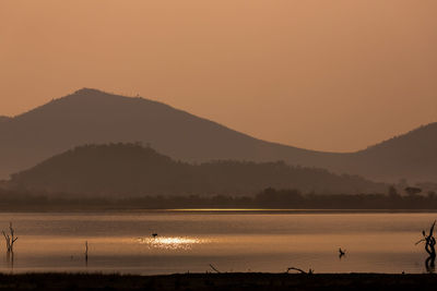 Scenic view of lake against orange sky