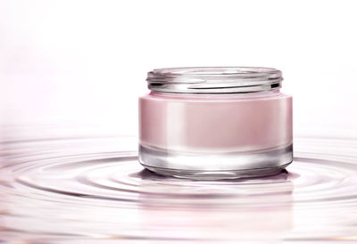 Close-up of glass of jar over white background