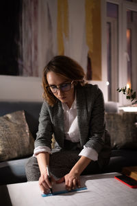 Young woman looking away while sitting on table