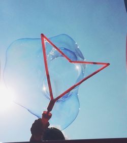 Low angle view of hand holding blue sky