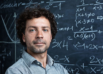 Portrait of teacher by blackboard in classroom