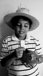 Boy with hat putting coin in piggy bank