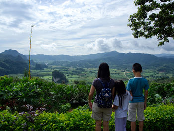 Rear view of people standing on mountain against sky