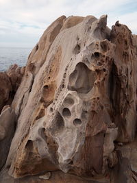 Close-up of rock formation on beach against sky