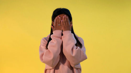 Portrait of young woman against yellow background