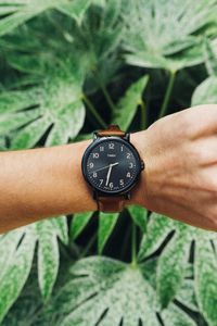 Close-up of hand holding clock against blurred background