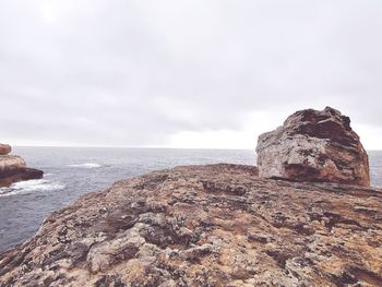 Rock formation on beach against sky