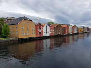 Houses by river against sky in city