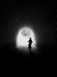 Rear view of silhouette man riding in tunnel
