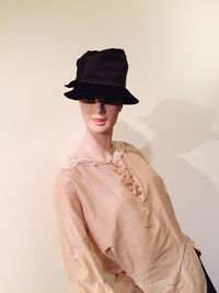 Mannequin in black hat against wall