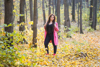 Full length of young woman standing in forest