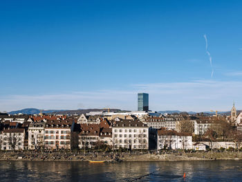 Buildings by river against blue sky