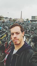 Portrait of man with bicycle in city against sky
