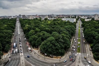 Road passing through city against cloudy sky