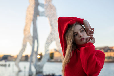 Beautiful young woman looking away against sky