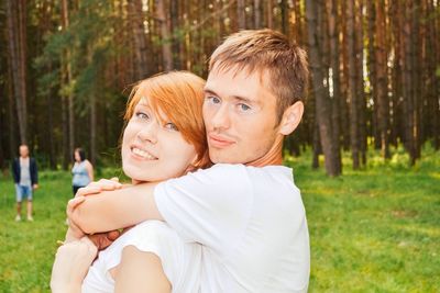Portrait of couple embracing against trees