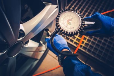 Cropped hands of mechanic examining car wheel in workshop