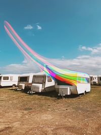 Digital composite image of camper vans with light trails on land