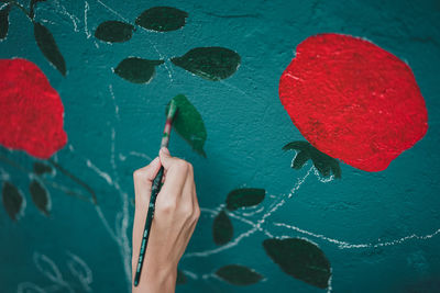 Cropped hand painting from flowers on wall