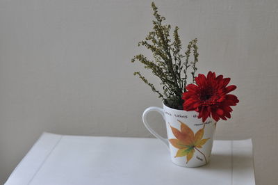 Close-up of white flower vase on table against wall