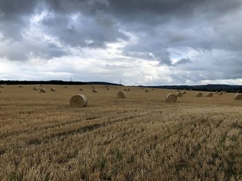 Hay bales on field against sky