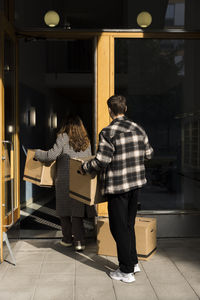 Multiracial couple carrying boxes while walking in apartment building