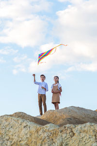 Classmates a boy and girl launch a kite standing on edge of the abyss.