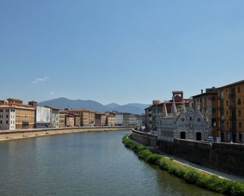 Buildings by river against sky