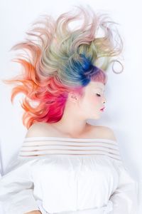 High angle view of young woman with dyed hair lying over white background