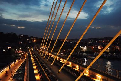 Illuminated bridge in city against sky at dusk