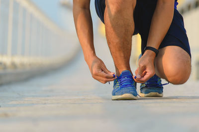 Low section of man tying shoelace