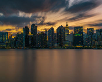 Illuminated buildings in city against sky during sunset