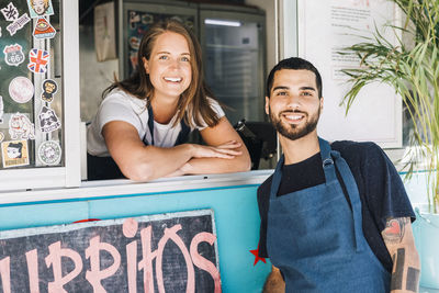 Portrait of smiling young male and female salesman at concession stand