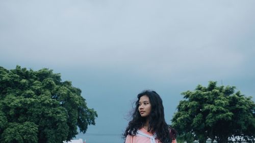 Young woman standing against sky