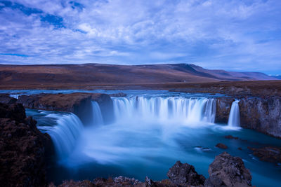 Scenic view of waterfall against sky