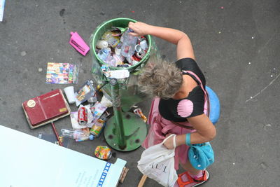 High angle view of woman throwing bottle in garbage bin on street
