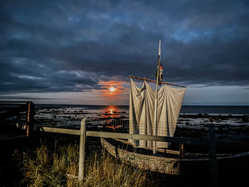 Built structure on beach against sky during sunset