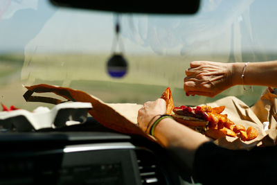 Woman's hands eating a hamburger inside a car, fast food