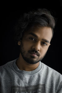 Portrait of young man against black background
