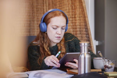 Young woman wearing headphones and studying