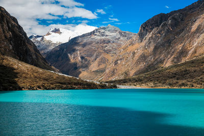 Scenic view of sea by mountains against blue sky