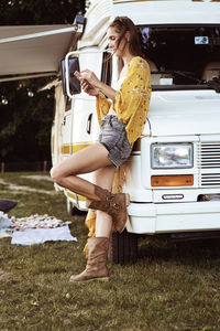 Side view of woman using smart phone by camper van