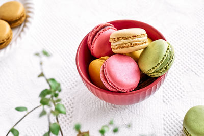 Colorful french macarons in pink bowl on white tablecloth. tasty cakes macaroon of different colors.