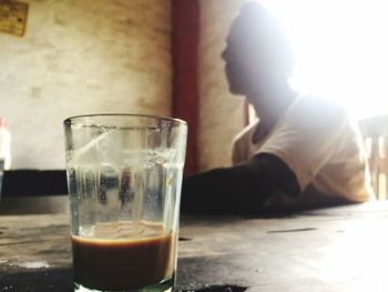 Reflection of man drinking glass on table