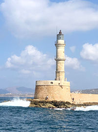 Lighthouse by sea against sky